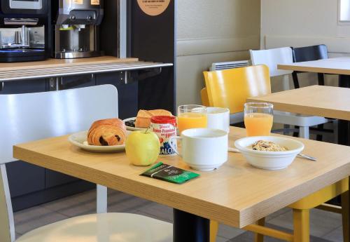 a table with breakfast foods and orange juice on it at B&B HOTEL Dijon Les Portes du Sud in Marsannay-la-Côte