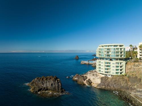 a tall building on the edge of a body of water at Pestana Vila Lido Madeira Ocean Hotel in Funchal