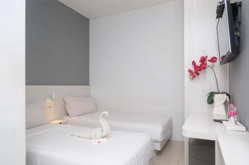 a white room with two beds and a swan on a table at Red Orchid Hotel by Sajiwa in Semarang
