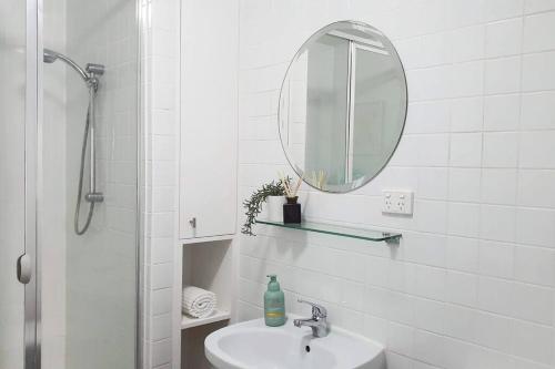 Baño blanco con lavabo y espejo en Marina Magic Getaways - Your Waterfront Retreat, en Patterson Lakes