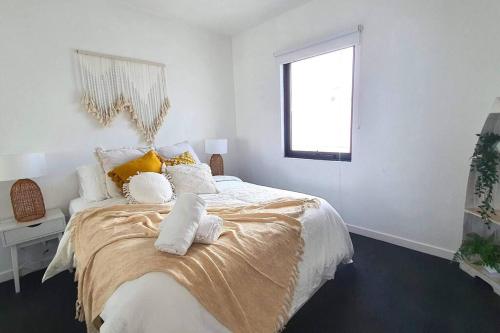 a white bedroom with a bed with towels on it at Marina Magic Getaways - Your Waterfront Retreat in Patterson Lakes