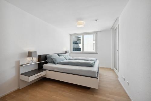 a white bedroom with a bed and a window at EXQUIS Design 2BR Apartment BAUHAUS I Balkon I Parkplatz I Top-Lage I Mercedes-Benz I Kinderbetten in Böblingen