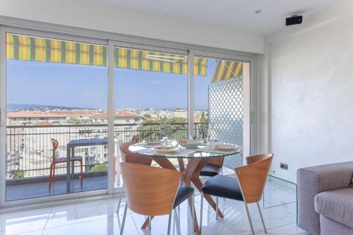 une salle à manger avec une table et des chaises et une grande fenêtre dans l'établissement Le Beauséjour by Halldis, à Cannes