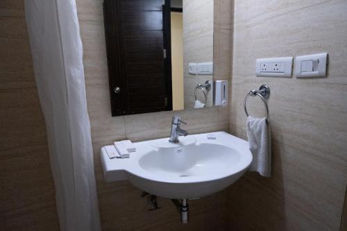 a bathroom with a white sink and a mirror at Hyphen Premier-Business Hotel in Meerut