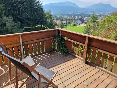 eine Holzterrasse mit einem Stuhl darauf in der Unterkunft Fridas Place - DER Blick über ganz Villach - 160 m2 Familienoase in Villach