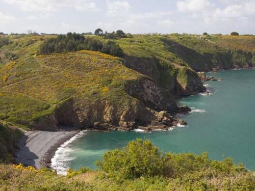 a view of a beach on a hill next to a body of water at Havre de paix proche de la mer, pointe de Pors Pin in Plouézec