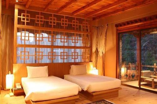 a bedroom with two beds in front of a window at Udumwara Resort in Paro