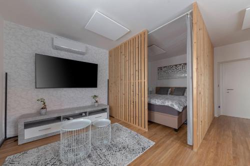 1 dormitorio con 1 cama y TV de pantalla plana en Apartments Grahek, en Liubliana