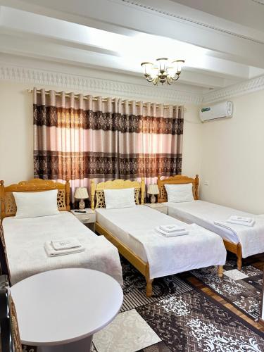 Habitación con 3 camas y mesa. en Hotel Mironshox en Bukhara
