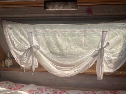 - une fenêtre avec un rideau au-dessus d'un lit dans l'établissement Tiny House Bohême pour amoureux en Day use 12 à 20H, à Pont-à-Celles