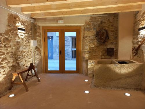 a large room with a stone wall and a door at Cal Vallverdú 2D in Preixana