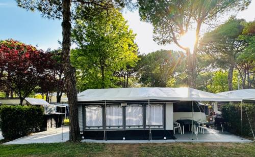 een tent met een tafel en stoelen in een tuin bij PS-Caravaning auf Union Lido - Wohnwagenvermietung in Cavallino-Treporti