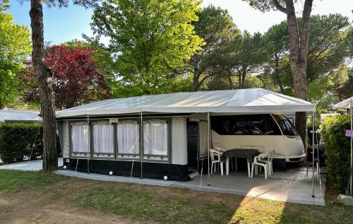 uma tenda branca com uma mesa e cadeiras em PS-Caravaning auf Union Lido - Wohnwagenvermietung em Cavallino-Treporti