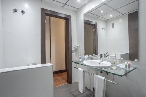 Baño blanco con lavabo y espejo en Hotel Monte Puertatierra en Cádiz