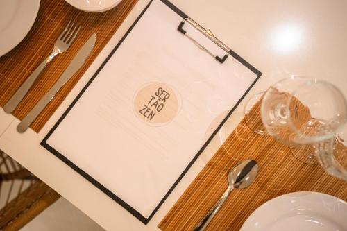 a table with a clipboard on a table with wine glasses at Casa com piscina privativa na Praia da Pipa #1 in Tibau do Sul