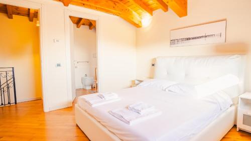um quarto com uma cama branca com duas toalhas em Villa Corte Barcuzzi - Italian Homing em Barcuzzi