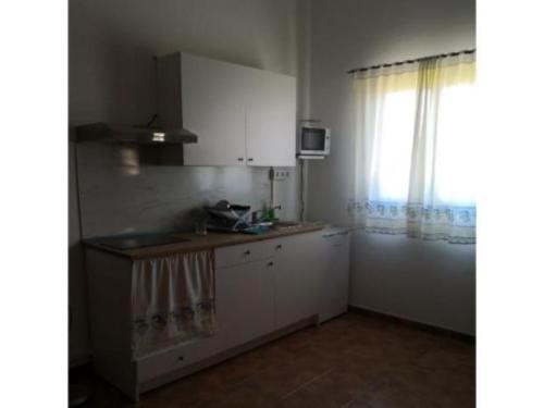 una cocina con armarios blancos y una ventana en Ca' Anibal en Tías