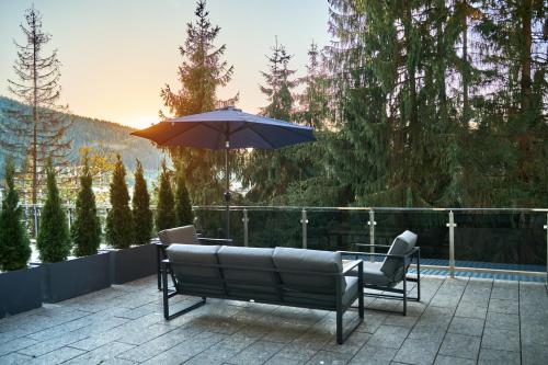 a patio with two chairs and an umbrella at Fomich Residence in Bukovel