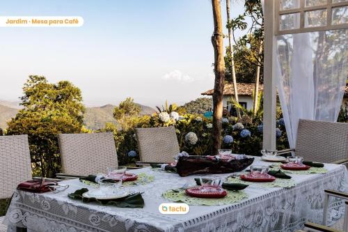 una mesa con un mantel blanco sobre una mesa con sillas en Pousada Le Monte Cristo c/ Café Guaramiranga en Guaramiranga