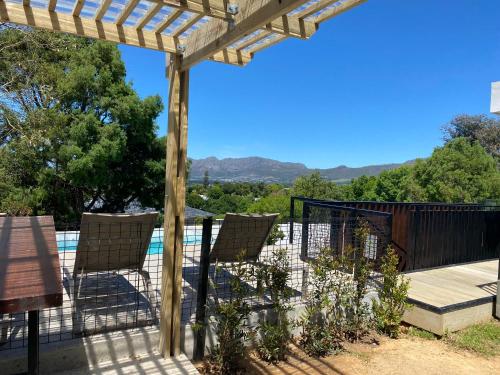 a deck with chairs and a pergola and a pool at Constantia View Apartments- Luxury Self Catering in Cape Town
