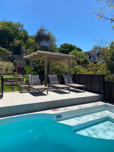 a swimming pool with two chairs and a gazebo at Constantia View Apartments- Luxury Self Catering in Cape Town