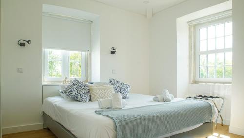 a white bedroom with a bed with blue and white pillows at Casa da Maria in Constância