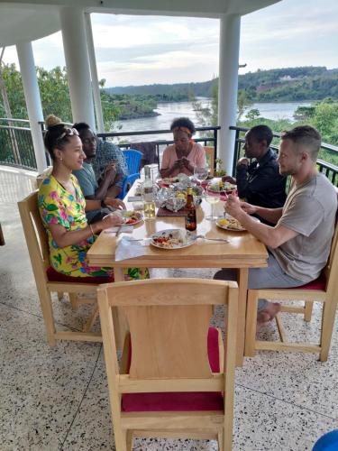 un grupo de personas sentadas en una mesa comiendo comida en Nile Retreat, en Jinja
