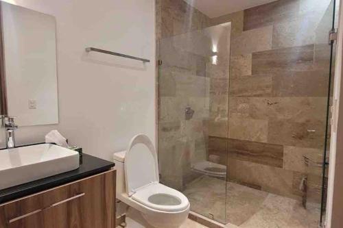 uma casa de banho com um WC e uma cabina de duche em vidro. em Ikaroa Luxury apartment direct on the beach AirB&B em Acapulco