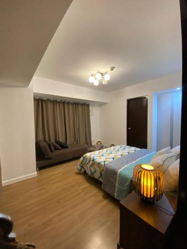 a bedroom with a bed and a couch at ABREEZA PLACE ONE BEDROOM SUITE (skyspot) in Davao City