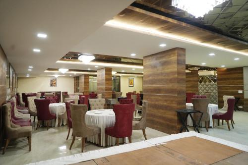 a dining room with white tables and red chairs at Hotel THE LAMP in Zirakpur