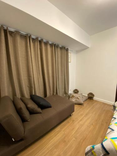 a couch sitting in a living room next to a curtain at ABREEZA PLACE ONE BEDROOM SUITE (skyspot) in Davao City