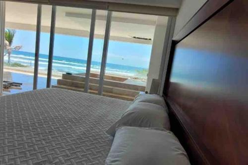 um quarto com uma cama e vista para a praia em Ikaroa Luxury apartment direct on the beach AirB&B em Acapulco