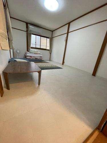 une pièce vide avec un lit et une table dans l'établissement AnNam Stay Osaka Airport, à Toyonaka
