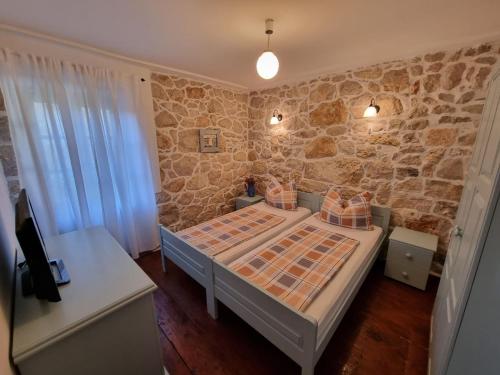 una camera da letto con un letto e un muro di pietra di Villa Supetarska Draga with 3 bedrooms in Rab a Supetarska Draga