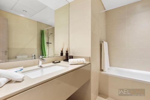 uma casa de banho com um lavatório, um espelho e uma banheira em WelHome - Apt Close to Yas Waterworld and Ferrari Circuits em Abu Dhabi