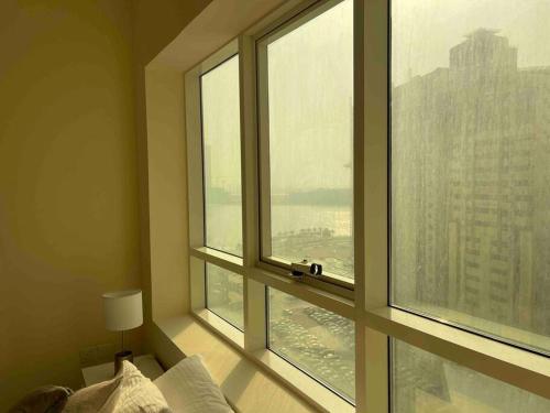 een slaapkamer met een groot raam met uitzicht op de stad bij deluxe apartment closed to beach in Sharjah