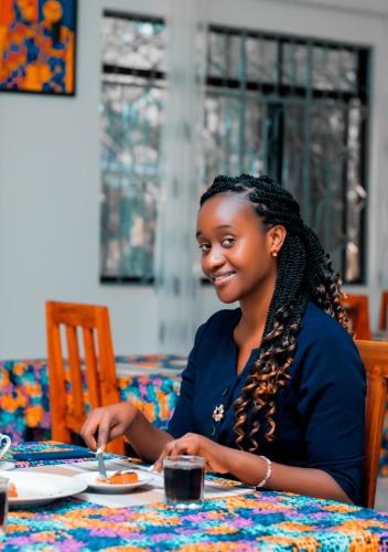 una donna seduta a un tavolo con un piatto di cibo di Charming Bungalows a Mwanza