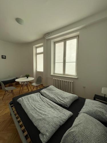 a bedroom with a bed and a table and windows at Room in Old Town Krakow in Kraków