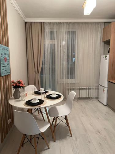 een eetkamer met een tafel en stoelen en een keuken bij Nurly Zhol apartment in Promyshlennyy