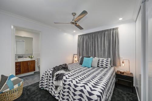 a bedroom with a black and white bed and a window at 12th Tee BnB in Bargara