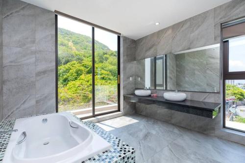 La salle de bains est pourvue d'une baignoire, de 2 lavabos et de fenêtres. dans l'établissement 31 Viba - Villa Vũng Tàu, à Vung Tau