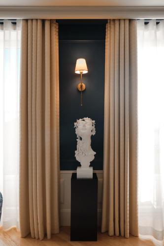 a lamp and a white statue in a room with curtains at GA Palace Hotel & Spa, a XIXth-Century Villa in Porto