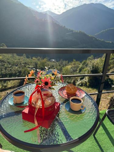a glass table with food and cups of coffee on a balcony at Eco cottage sunrise merisi in Merisi
