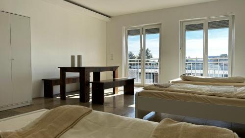 a room with two beds and a desk and windows at Pension MC City in Gaimersheim