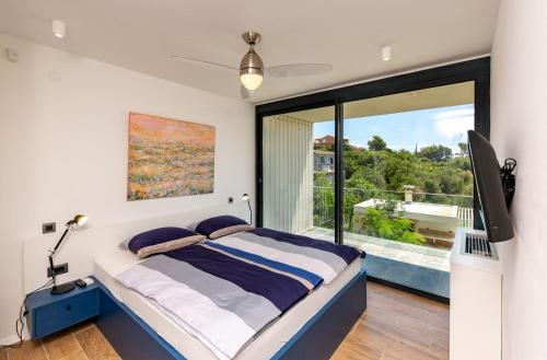 a bedroom with a bed and a large window at Luxury villa Mar with infinity pool in Rab in Palit