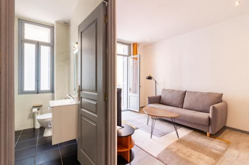 un soggiorno con divano e lavandino di Appartement moderne et élégant quartier Saint-Jean Perpignan 2 a Perpignano