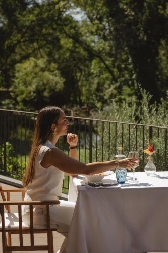 a woman sitting at a table with a glass of wine at Ribeira Collection Hotel by Piamonte Hotels in Arcos de Valdevez