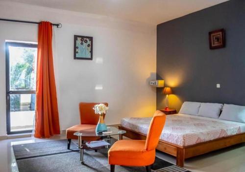 a bedroom with a bed and a chair and a window at Residence Hotel La Marsu in Cap Skirring
