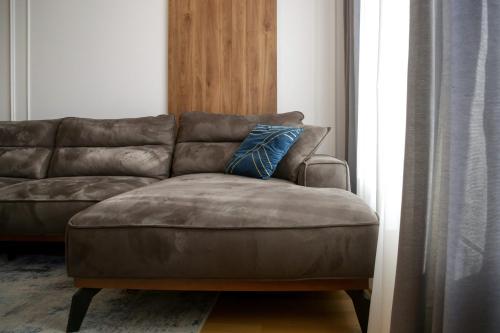 a brown leather couch with a blue pillow on it at Supernova Royal Residence in Novi Sad
