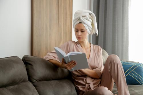 a woman sitting on a couch reading a book at Supernova Royal Residence in Novi Sad